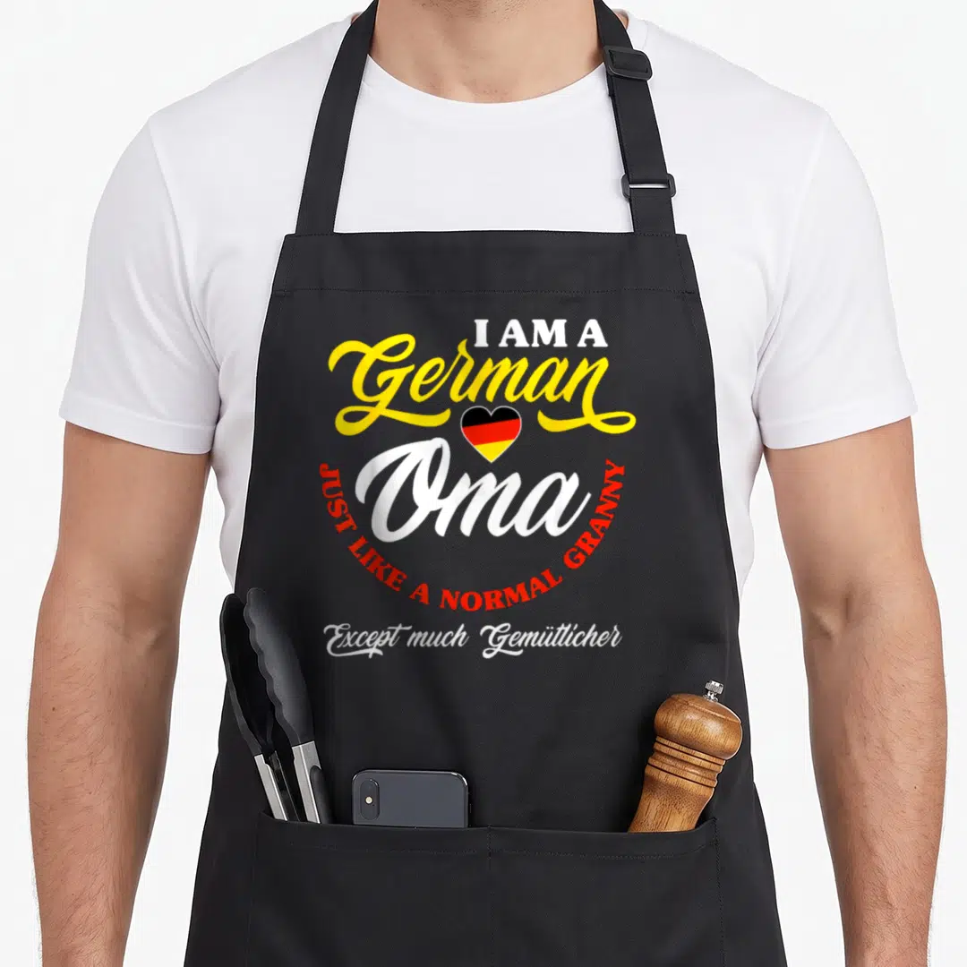 Germany granny apron - Stacked text I Am A German Oma with tricolor heart and curved red lettering — shown on a black cotton canvas apron against a white background