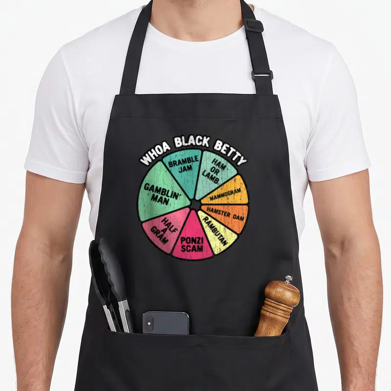 Whoa 70s apron - Whoa Black Betty wheel with segments reading Bramble Jam Ham or Lamb Ponzi Scam — shown on a black cotton canvas apron against a white background