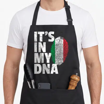 Dna italian aprons - Stacked IT'S IN MY DNA text beside a white green and red distressed fingerprint — shown on a black cotton canvas apron against a white background