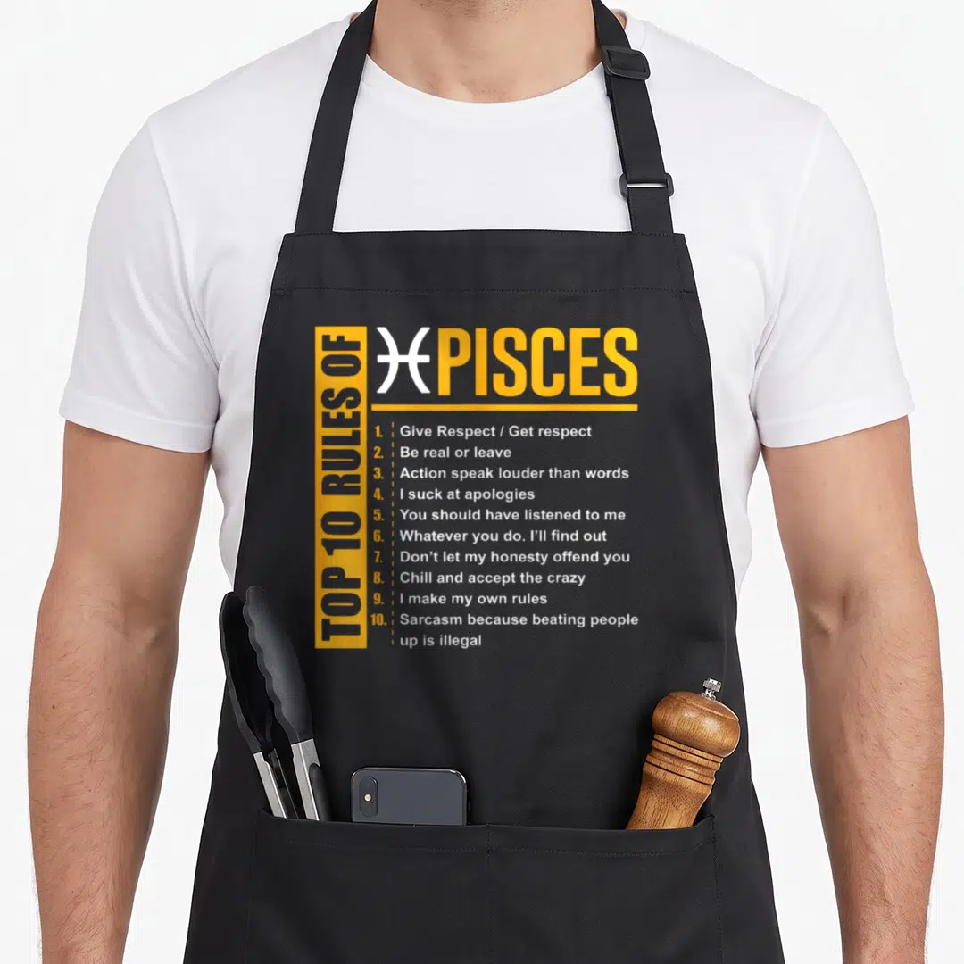 Rule birthday apron - Yellow and white Top 10 Rules of Pisces typography listing sarcastic zodiac guidelines — shown on a black cotton canvas apron against a white background