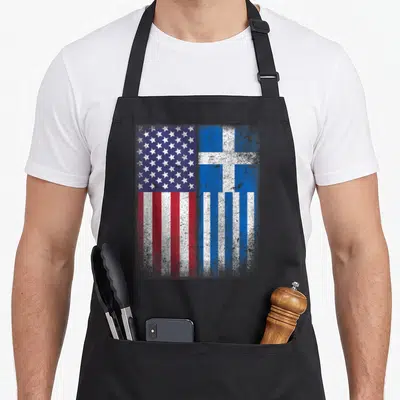 Hellas american flag apron - Distressed USA and Greece flags side by side in red white blue — shown on a black cotton canvas apron against a white background