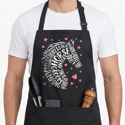 Typography equestrian horse apron - White equestrian words forming a horse head with pink hearts and stars — shown on a black cotton canvas apron against a white background