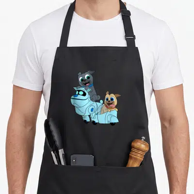 Rolly dog apron - Grey cartoon dog on blue robot vehicle with tan dog passenger — shown on a black cotton canvas apron against a white background
