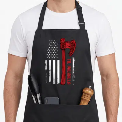 Viking american flag apron - Red axe next to distressed white stars and stripes with vertical red text reading Til — shown on a black cotton canvas apron against a white background