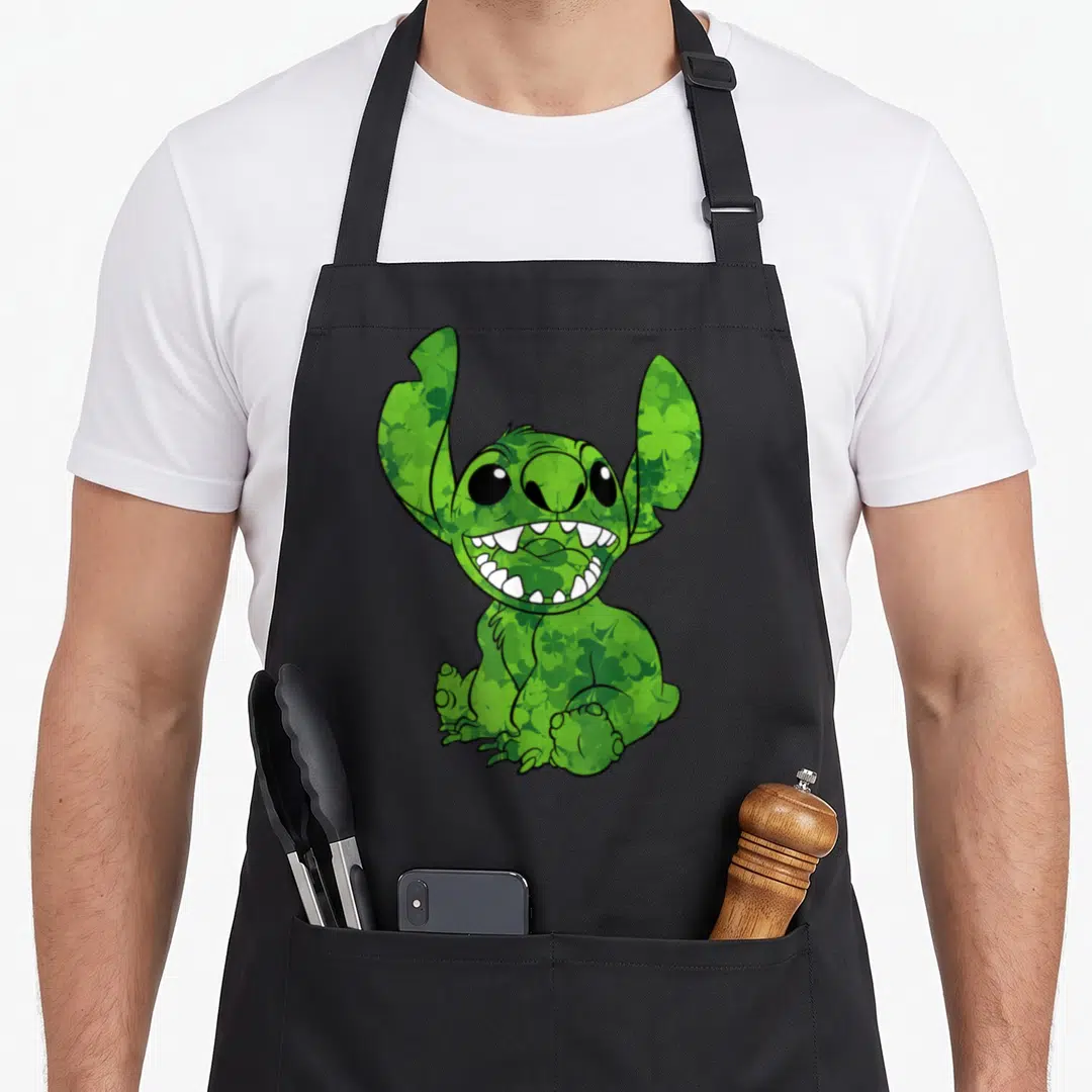 Fill st patrick day aprons - Green Stitch character filled with shamrock patterns, cartoon style, black outlines — shown on a black cotton canvas apron against a white background