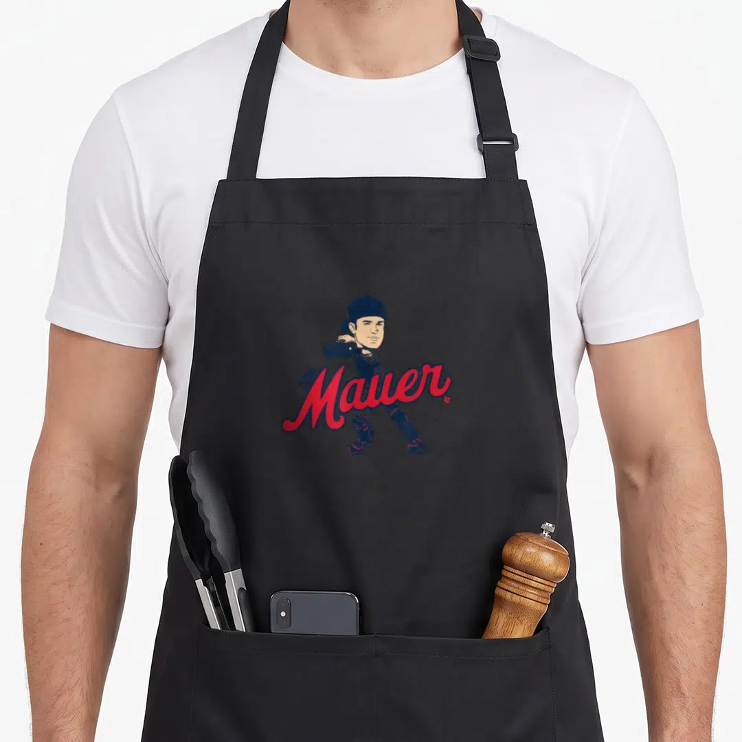 Joe minnesota aprons - Cartoon Joe Mauer catcher behind red script text with navy and red gear — shown on a black cotton canvas apron against a white background