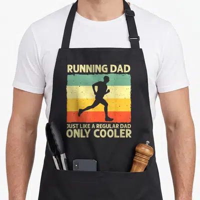 Running marathon apron - Retro runner silhouette on beige green yellow orange red stripes with Running Dad text — shown on a black cotton canvas apron against a white background