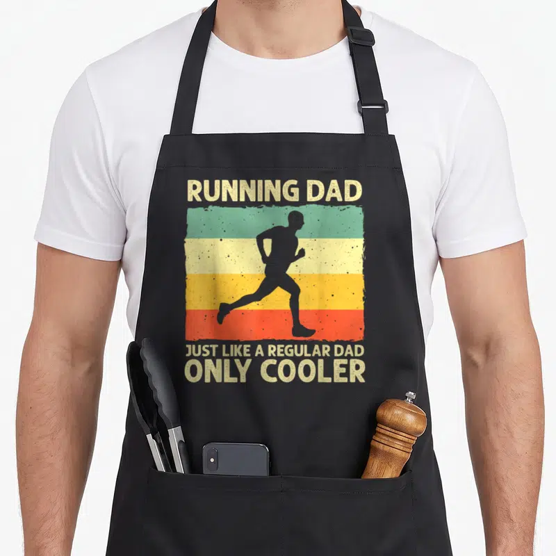 Running marathon apron - Retro runner silhouette on beige green yellow orange red stripes with Running Dad text — shown on a black cotton canvas apron against a white background