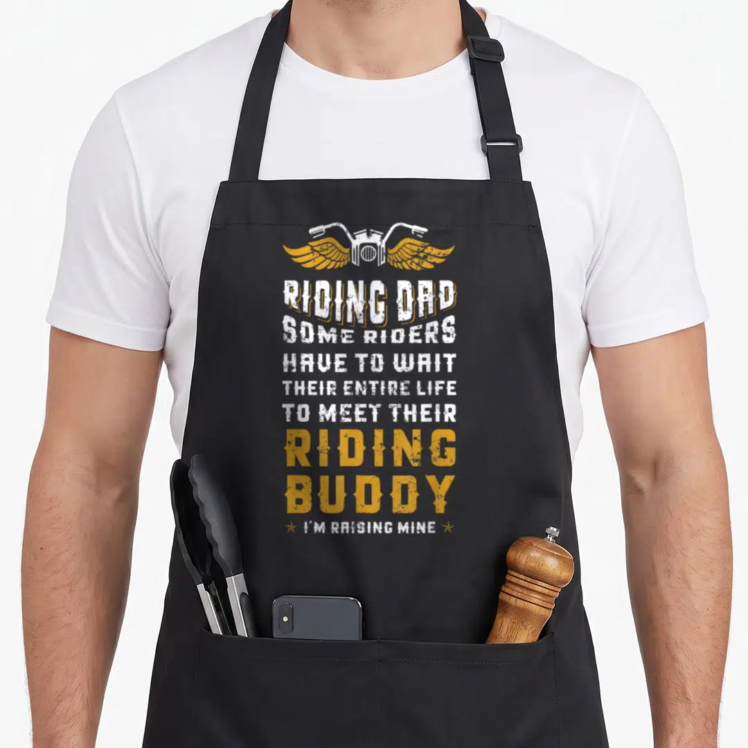 Biker father son apron - Winged handlebars and text Riding Dad Some Riders Have To Wait Their Entire Life To Meet — shown on a black cotton canvas apron against a white background
