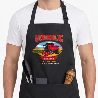 Combine farm apron - Red combine harvester in field with Agriholic text and EST 1868 ribbon — shown on a black cotton canvas apron against a white background