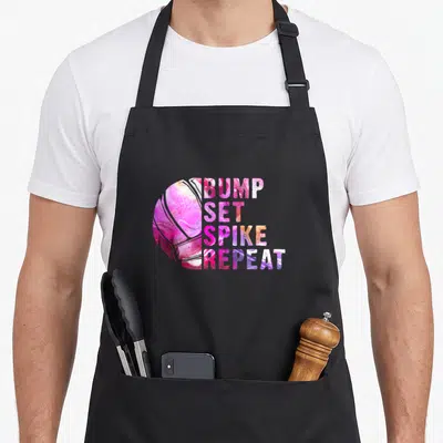 Bump spikeball apron - Marble pink purple volleyball next to stacked BUMP SET SPIKE REPEAT text — shown on a black cotton canvas apron against a white background