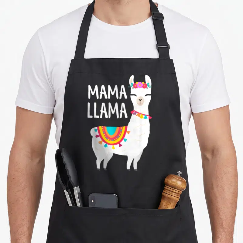 Mama mother's day aprons - Cartoon white llama wearing flower crown and blanket next to stacked MAMA LLAMA text — shown on a black cotton canvas apron against a white background
