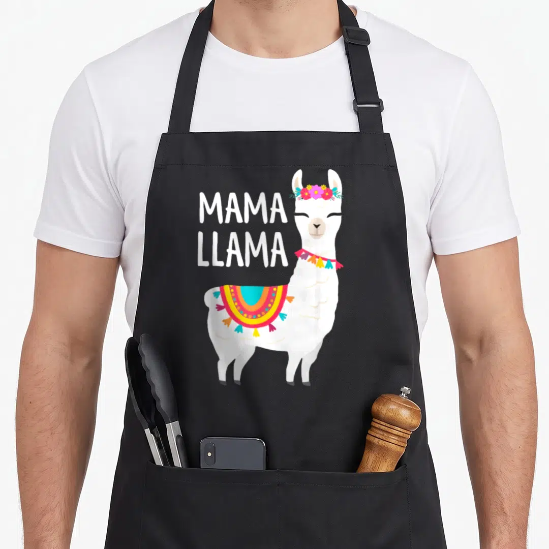Mama mother's day aprons - Cartoon white llama wearing flower crown and blanket next to stacked MAMA LLAMA text — shown on a black cotton canvas apron against a white background