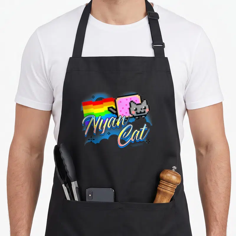 Airbrush cat apron - Pixel Nyan Cat with pink Pop-Tart body, rainbow trail, and script text in blue and pink — shown on a black cotton canvas apron against a white background