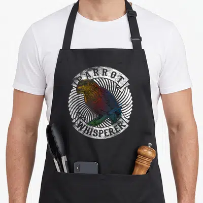 Whisperer colorful aprons - Distressed parrot perched in sunburst with arched text — shown on a black cotton canvas apron against a white background