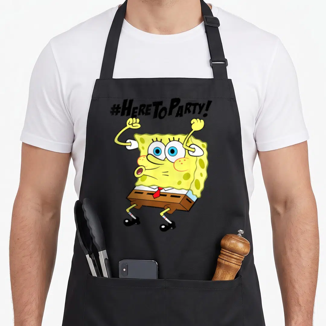 Funny squarepant novelty apron - SpongeBob with raised arms under '#HERE TO PARTY!' text in yellow brown and red — shown on a black cotton canvas apron against a white background