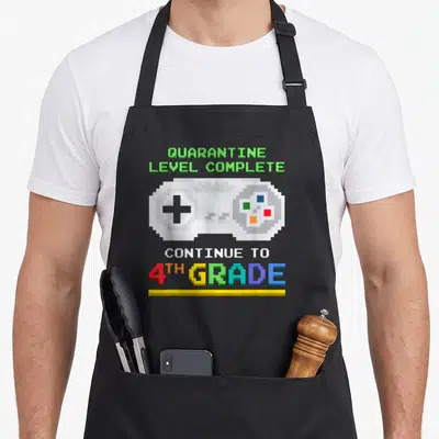 Level quarantine aprons - Pixel game controller with QUARANTINE LEVEL COMPLETE and 4TH GRADE text in rainbow colors — shown on a black cotton canvas apron against a white background