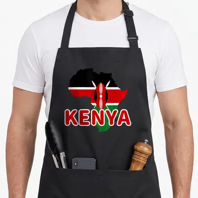 Kenya kenyan pride apron - Map of Africa silhouette filled with Kenyan flag stripes and central shield emblem — shown on a black cotton canvas apron against a white background