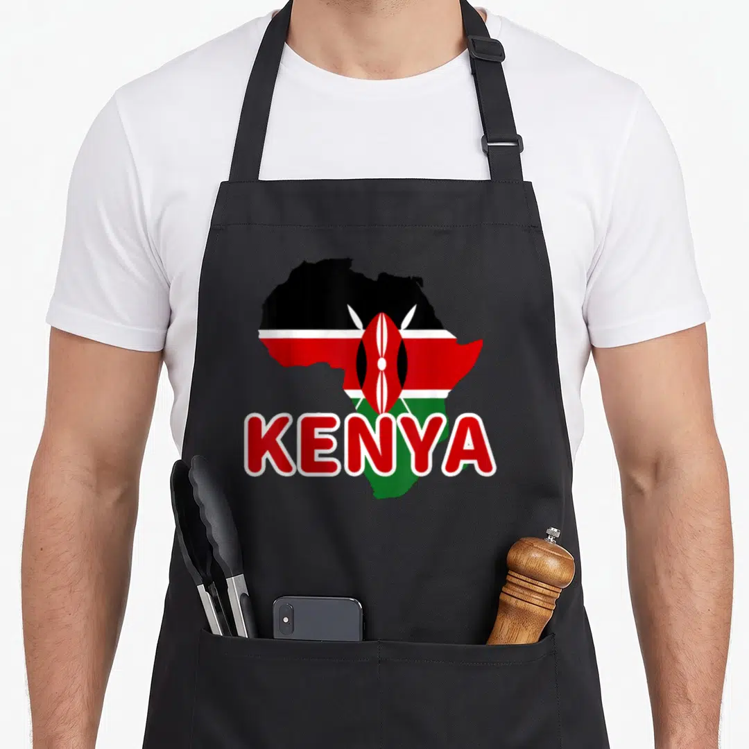 Kenya kenyan pride apron - Map of Africa silhouette filled with Kenyan flag stripes and central shield emblem — shown on a black cotton canvas apron against a white background