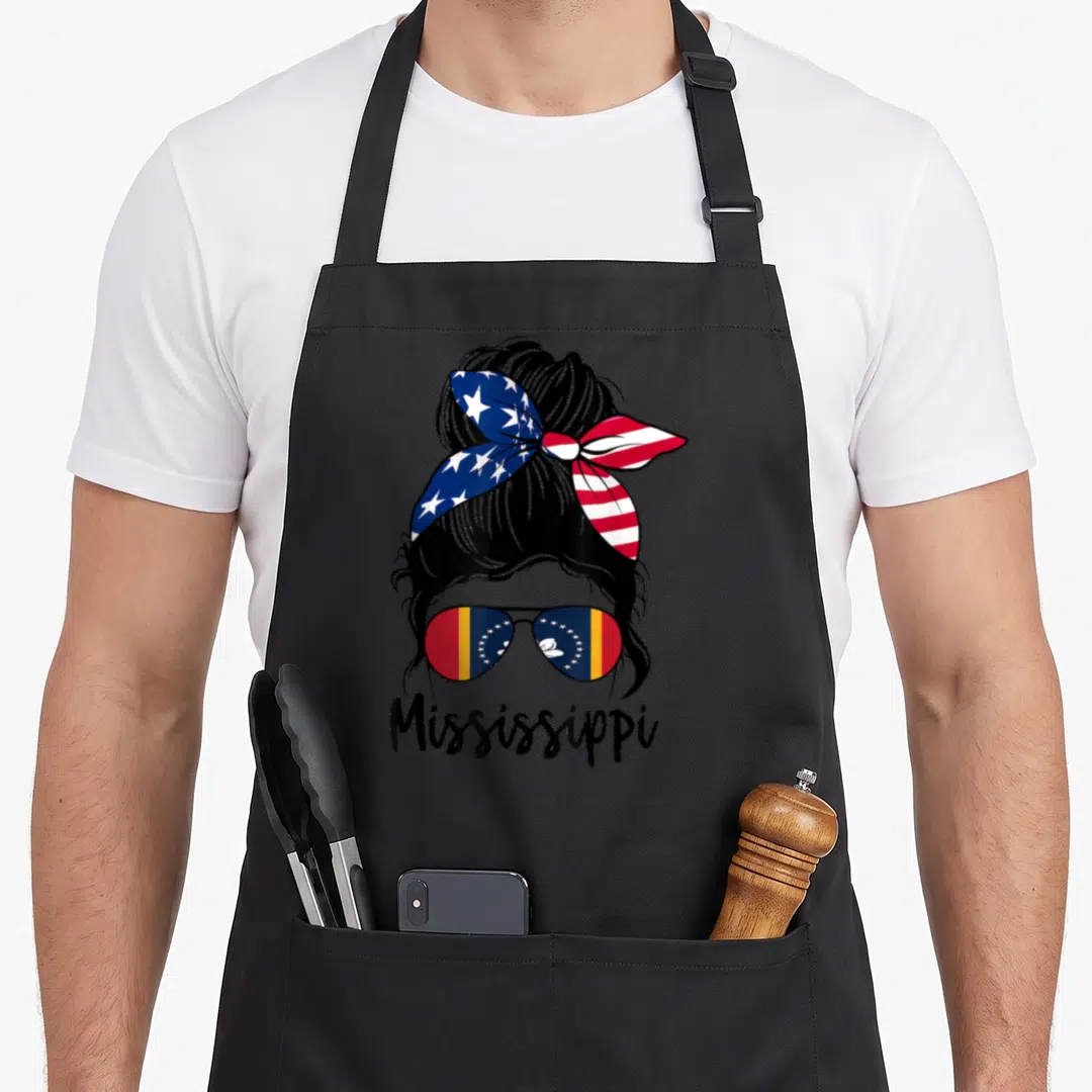 Flag mississippi girl apron - Cartoon woman with US headband and Mississippi flag sunglasses above printed text — shown on a black cotton canvas apron against a white background