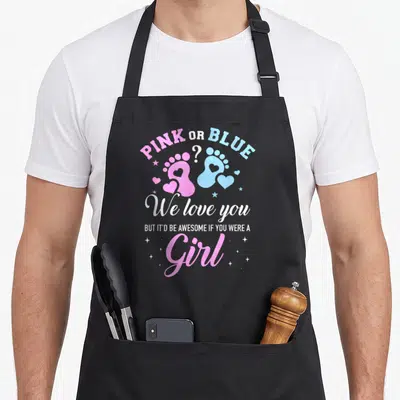 General apron or apron - PINK OR BLUE text over pink and blue baby footprints with hearts and stars — shown on a black cotton canvas apron against a white background