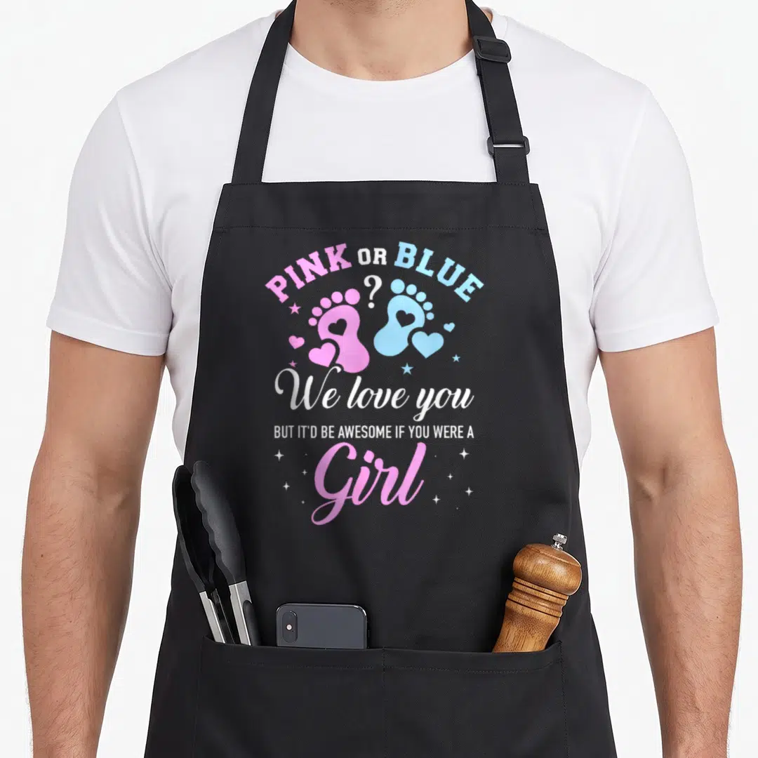 General apron or apron - PINK OR BLUE text over pink and blue baby footprints with hearts and stars — shown on a black cotton canvas apron against a white background