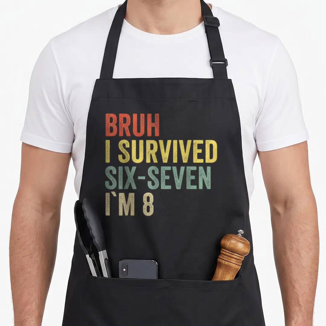 8th meme apron - Stacked text reading BRUH I SURVIVED SIX-SEVEN I'M 8 in red, yellow, green, and beige distressed font — shown on a black cotton canvas apron against a white background