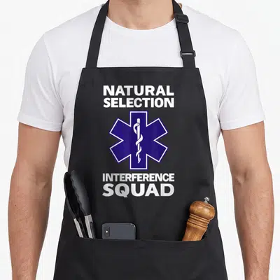 Natural squad funny apron - Star of Life symbol between white text reading NATURAL SELECTION and INTERFERENCE SQUAD — shown on a black cotton canvas apron against a white background