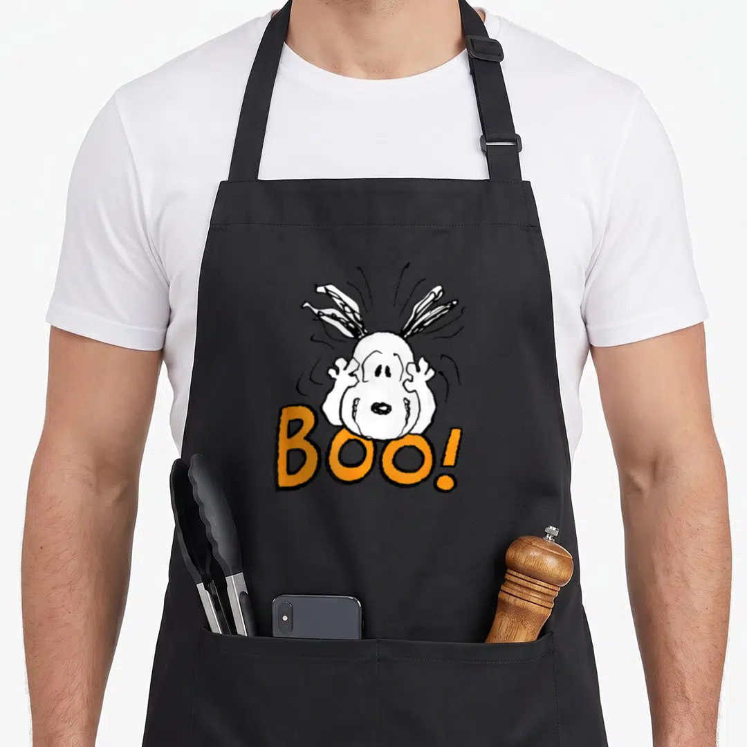 Cool boo halloween apron - White cartoon ghost with raised hands above orange BOO text on black background — shown on a black cotton canvas apron against a white background