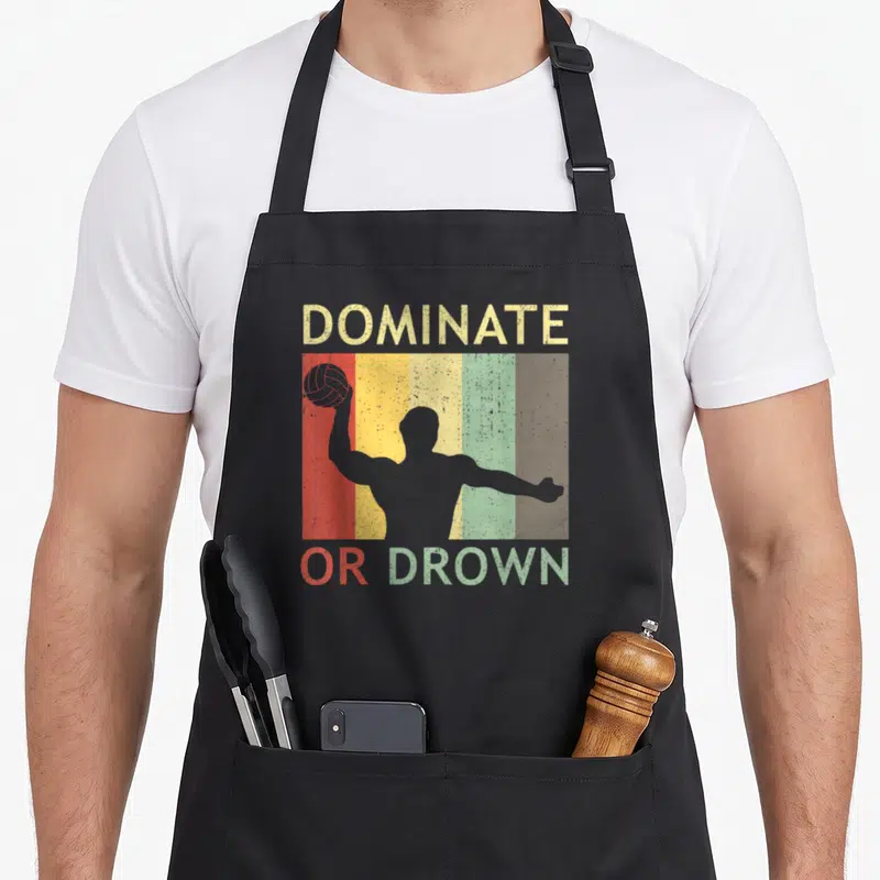 Water polo apron - Retro DOMINATE OR DROWN text with player silhouette over five colored stripes — shown on a black cotton canvas apron against a white background