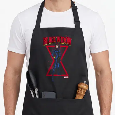 Stance hobby apron - Arched BLACK WIDOW text above blue character and red hourglass on spider web background — shown on a black cotton canvas apron against a white background