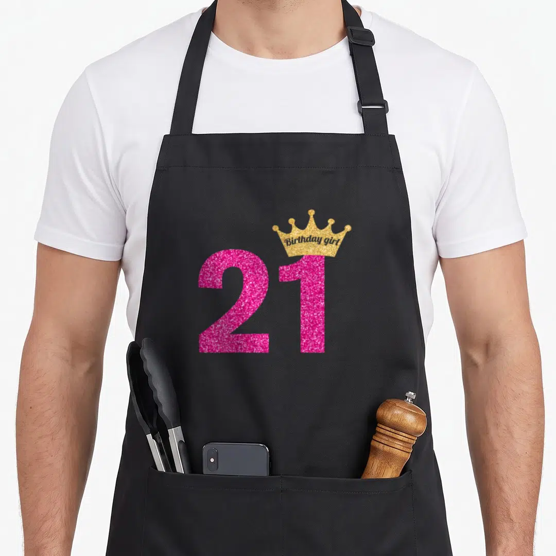 21st birthday princess apron - Pink glitter 21 with gold crown containing Birthday girl text — shown on a black cotton canvas apron against a white background