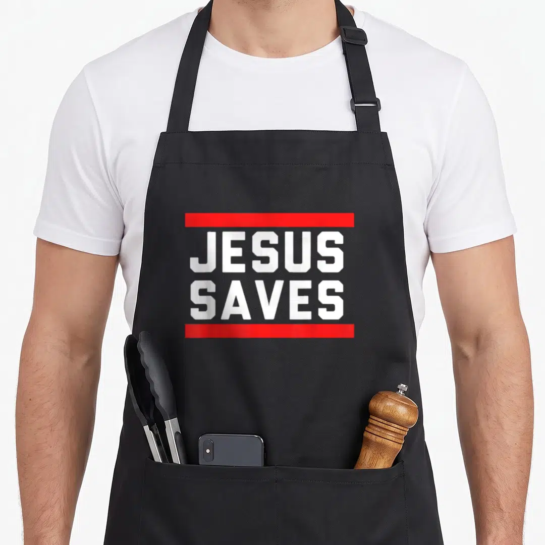 Religious faith christian apron - JESUS SAVES white text stacked between two horizontal red bars — shown on a black cotton canvas apron against a white background