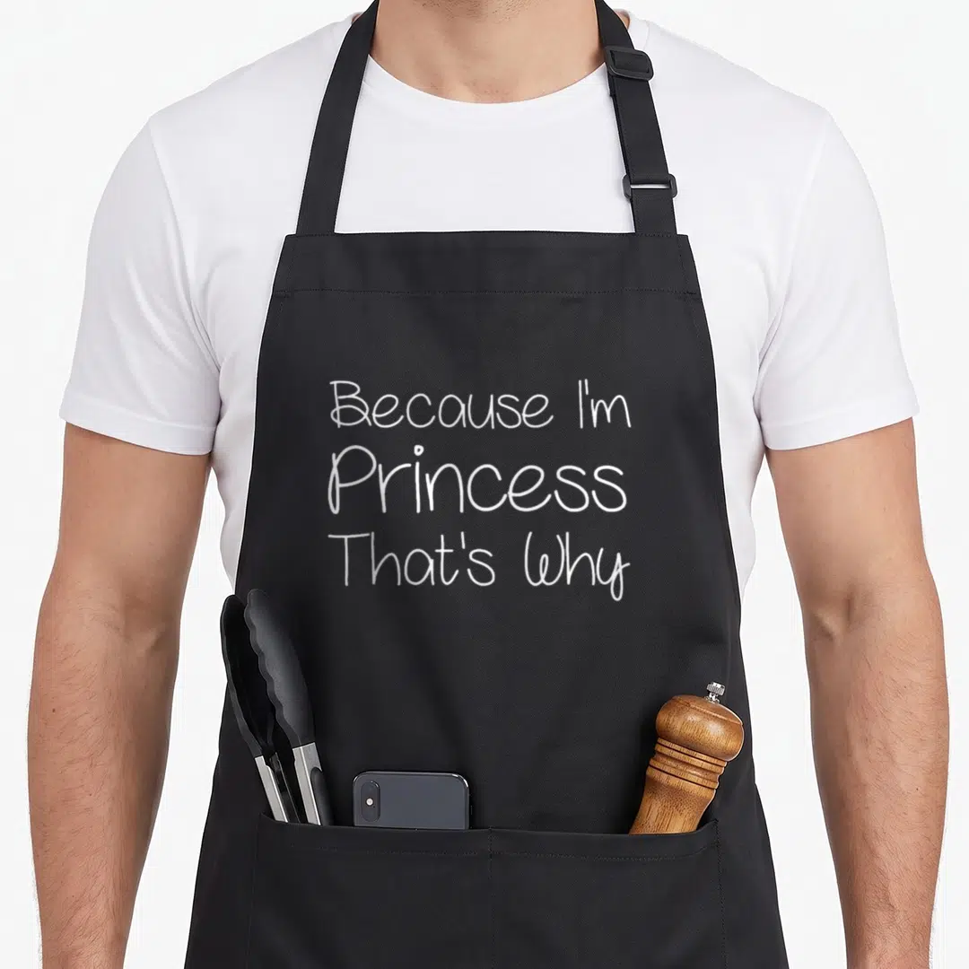 Mother christmas aprons - White script text Because I'm Princess That's Why stacked three lines on grey background — shown on a black cotton canvas apron against a white background