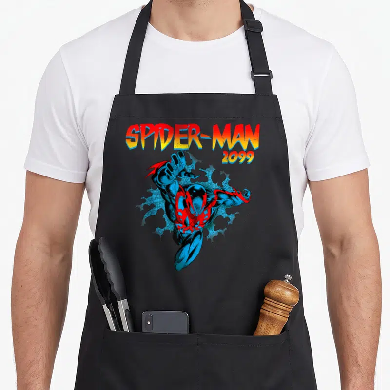 Jump spider apron - Spider-Man 2099 leaping through blue brick wall with gradient text — shown on a black cotton canvas apron against a white background
