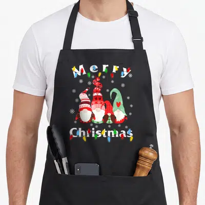 Gnome christmas lights apron - Four gnomes in a row with Merry Christmas text and colorful lights — shown on a black cotton canvas apron against a white background