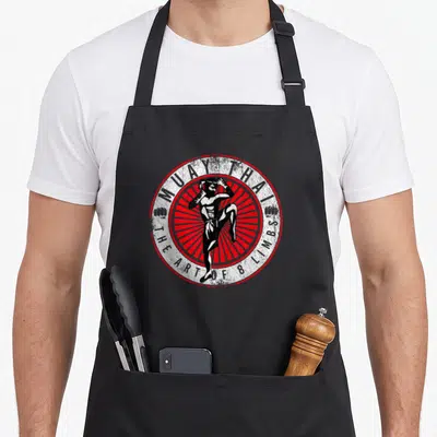 Muay thai kickboxing apron - Distressed fighter over red sunburst circle with Muay Thai text — shown on a black cotton canvas apron against a white background