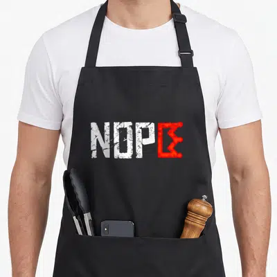 Nope king apron - Distressed white text NOPE with red crown shaped E on black background — shown on a black cotton canvas apron against a white background