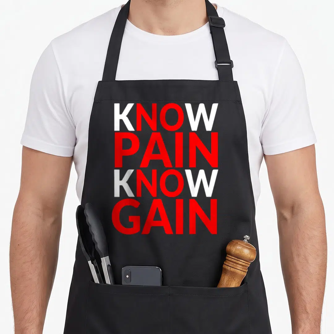 Exercise gains apron - Stacked red and white text reading KNOW PAIN KNOW GAIN on black fabric — shown on a black cotton canvas apron against a white background