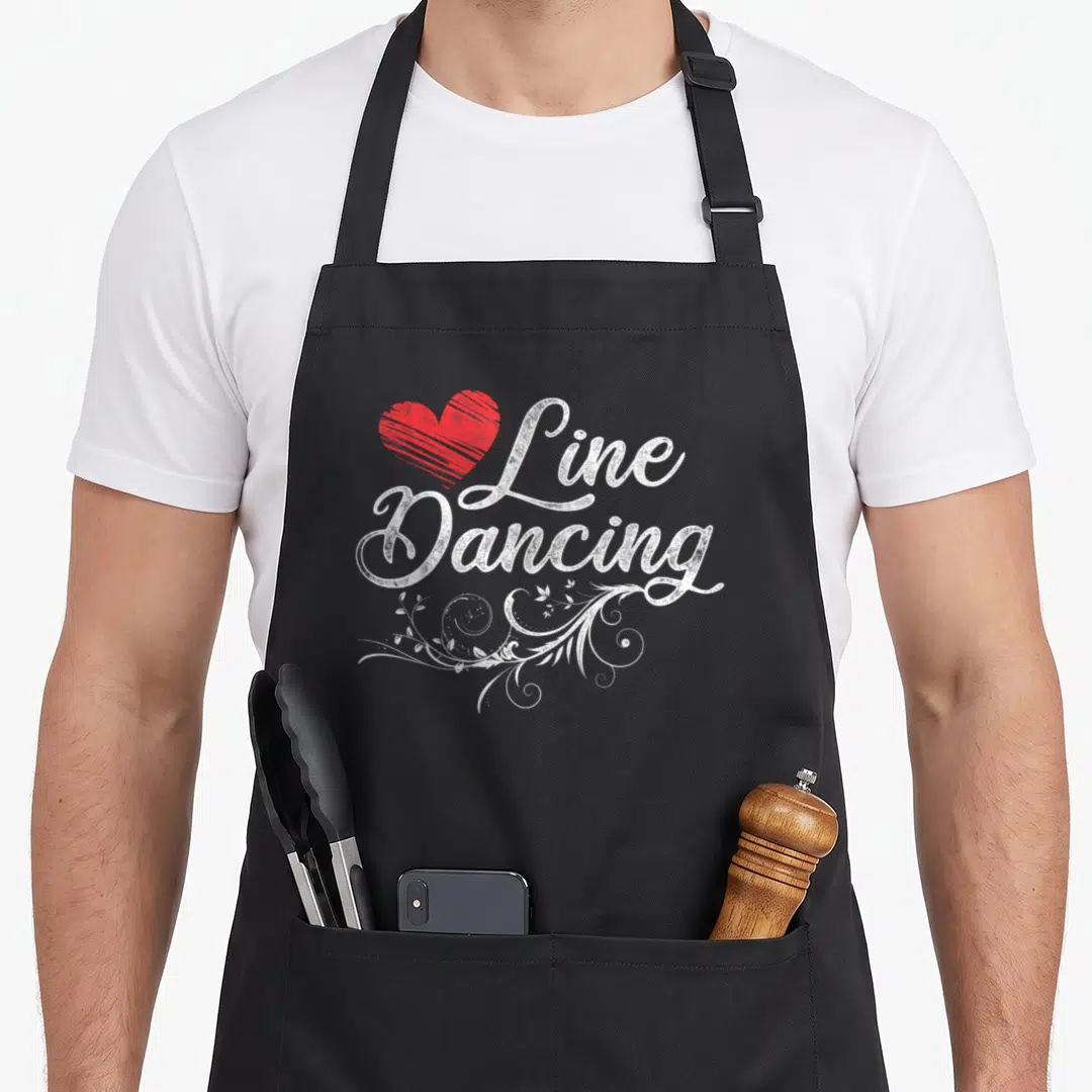 Dance line apron - Red heart beside white Line Dancing text with floral swirls — shown on a black cotton canvas apron against a white background