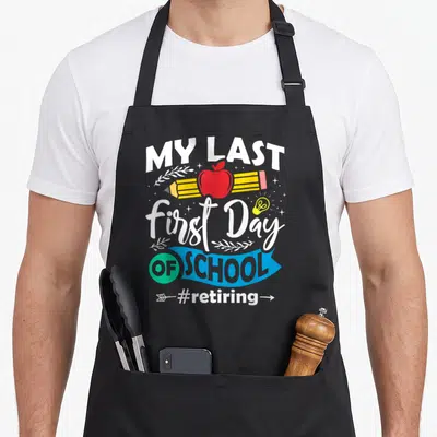 Retiring teacher apron - Stacked text My Last First Day OF SCHOOL with apple pencil and lightbulb in white blue red — shown on a black cotton canvas apron against a white background