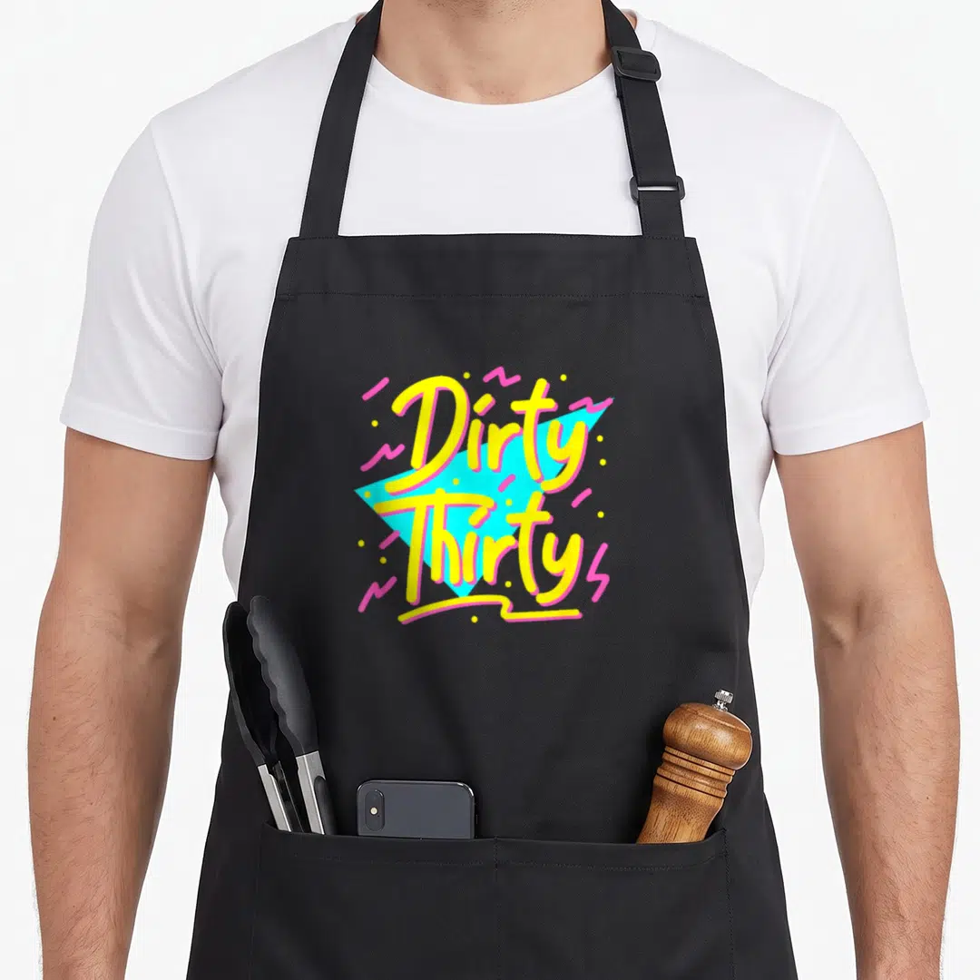 90s funny dirty aprons - Stacked Dirty Thirty text in yellow over cyan triangle with pink squiggles and yellow dots — shown on a black cotton canvas apron against a white background
