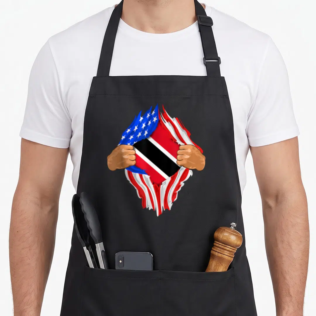 Trinidad blood apron - Two hands tearing fabric to reveal Trinidad and Tobago flag under US flag pattern in red white — shown on a black cotton canvas apron against a white background