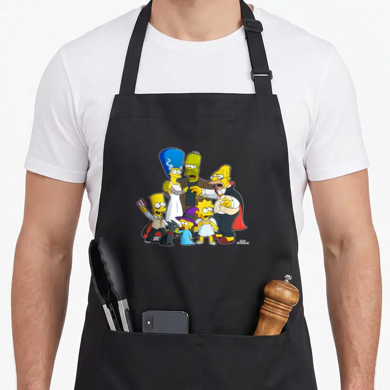 Family halloween apron - Simpsons family in Halloween costumes including vampire, mummy, witch, angel, and black cat — shown on a black cotton canvas apron against a white background