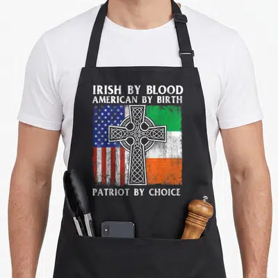 Blood ireland apron - Distressed Celtic cross over split US and Ireland flags with patriotic text — shown on a black cotton canvas apron against a white background