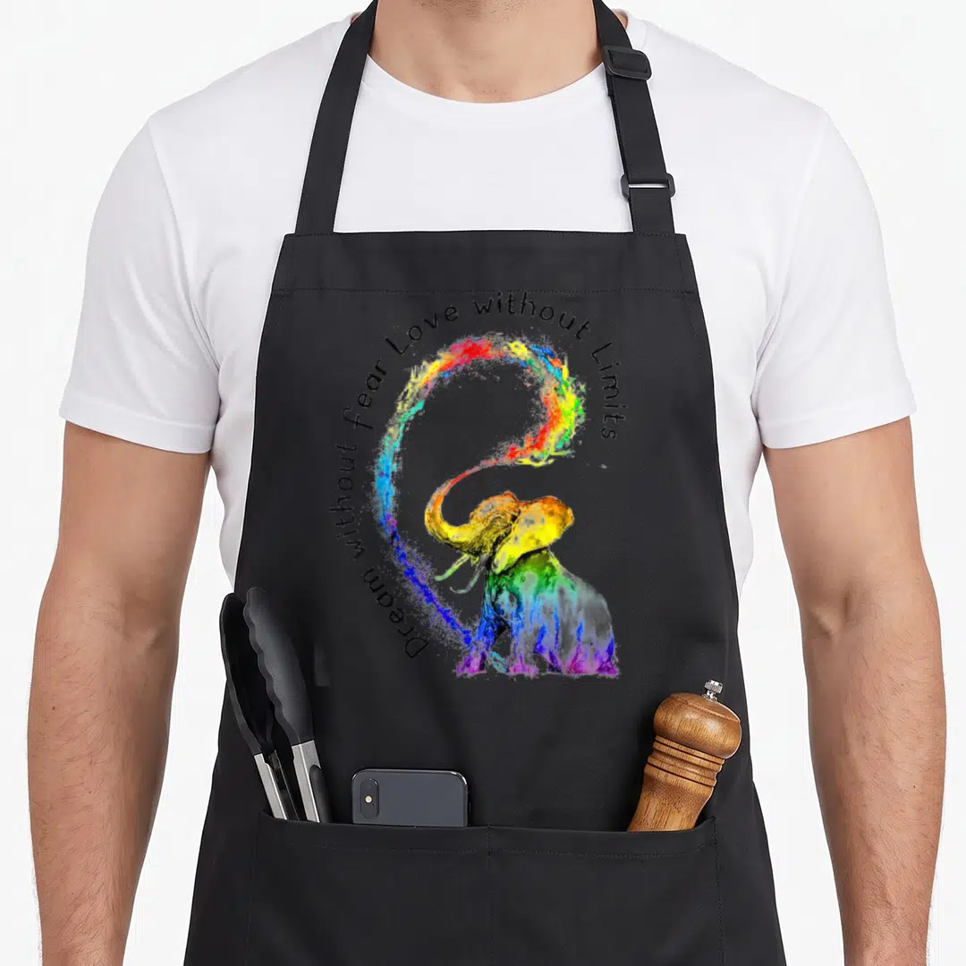 Dream fear apron - Rainbow watercolor elephant with arched text Dream without fear Love without Limits — shown on a black cotton canvas apron against a white background