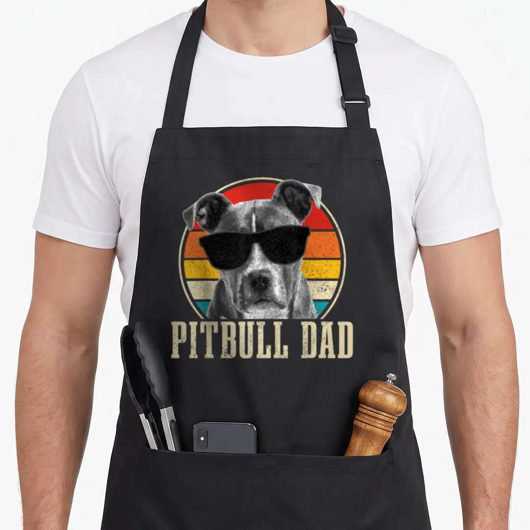 Sunglass custom dog apron - Retro pitbull wearing sunglasses in front of a striped sun with text below — shown on a black cotton canvas apron against a white background