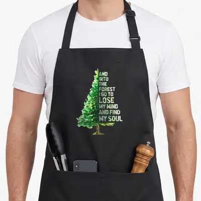 Mind find aprons - Watercolor tree with stacked text reading And Into The Forest I Go To Lose My Mind And Find My Soul — shown on a black cotton canvas apron against a white background