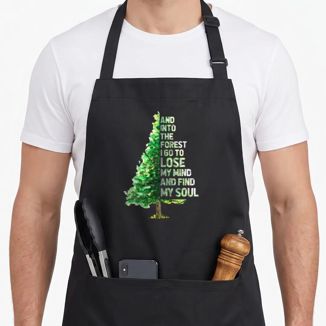 Mind find aprons - Watercolor tree with stacked text reading And Into The Forest I Go To Lose My Mind And Find My Soul — shown on a black cotton canvas apron against a white background