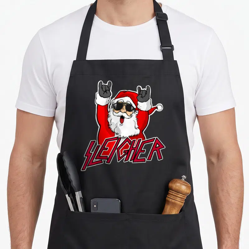 Metal santa claus apron - Cartoon Santa with sunglasses making rock horns above SLEIGHER text in red and black — shown on a black cotton canvas apron against a white background